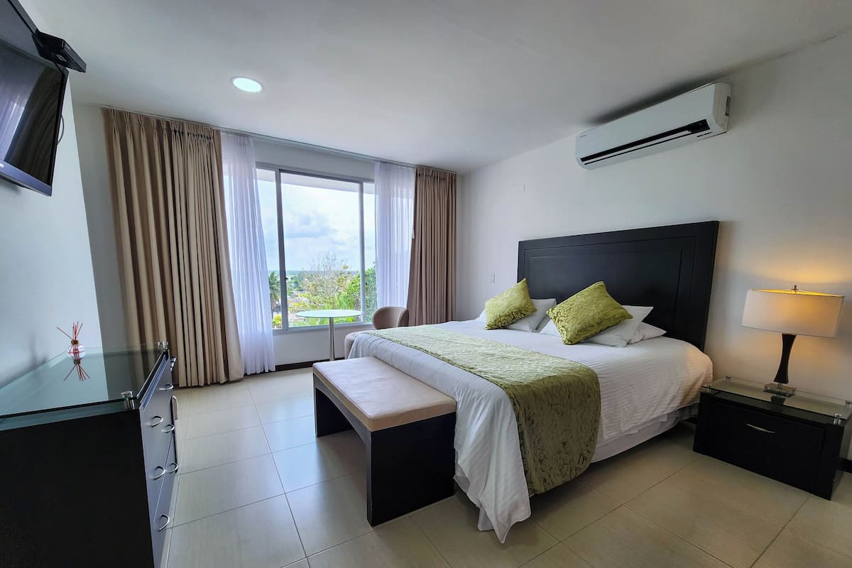 A hotel room with a bed, bedside tables, a desk, and a window with curtains.