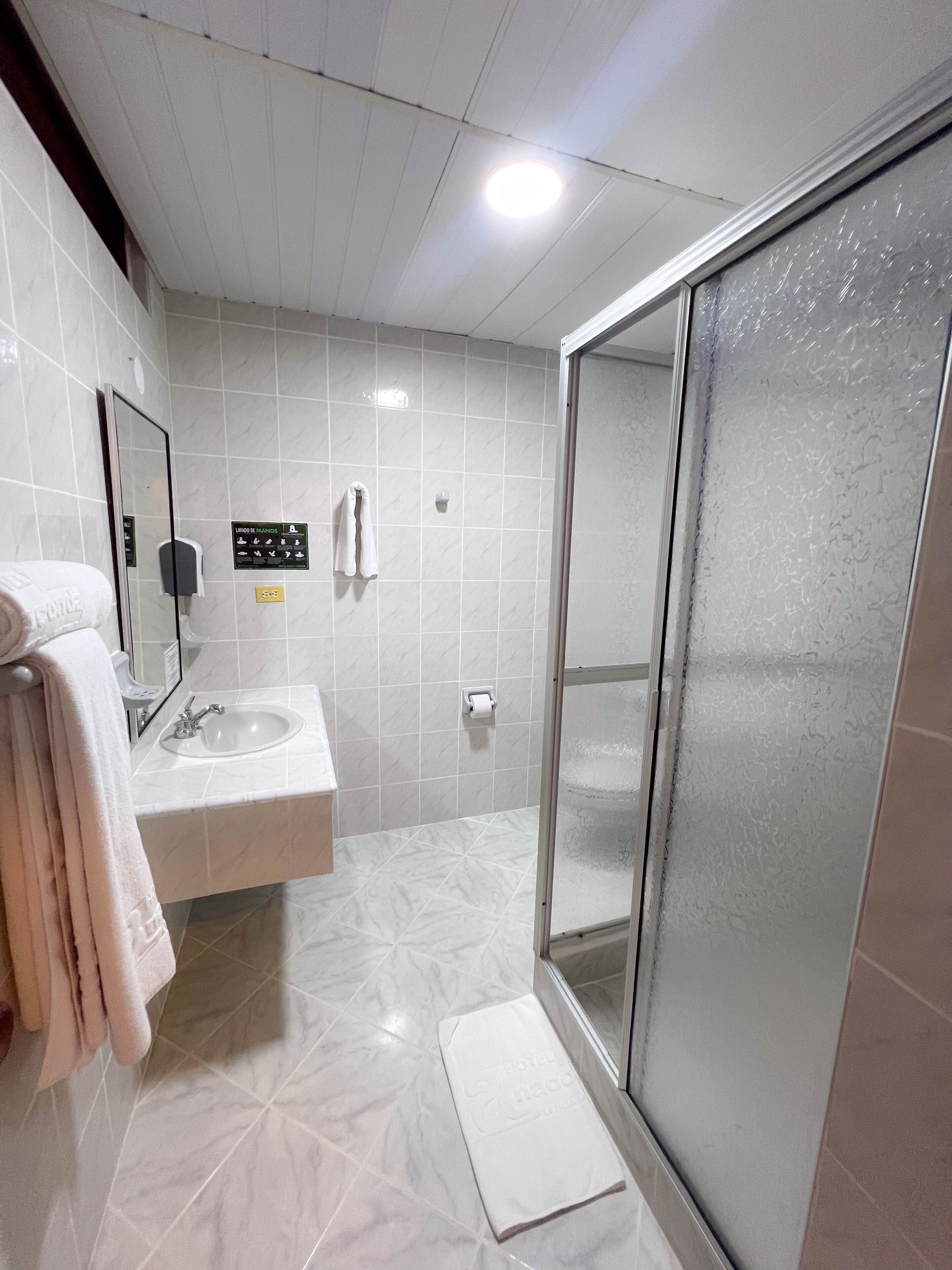 Une salle de bain moderne dotée d’une douche à parois de verre, d’un lavabo et d’un porte-serviettes.