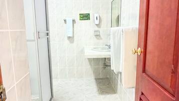 Une salle de bain avec une douche à parois de verre, un lavabo, un miroir et un porte-serviettes.