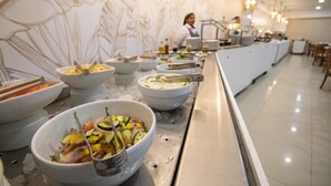 A buffet area with various dishes, a chef in the background, and a decorative wall. - Hotel El Dorado (San Andrés)