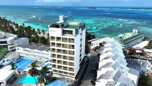 A hotel with multiple floors, a swimming pool, and a view of the ocean. - Hotel El Dorado (San Andrés)