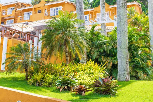 Un hotel con varias edificaciones amarillas, palmeras y un jardín bien cuidado.