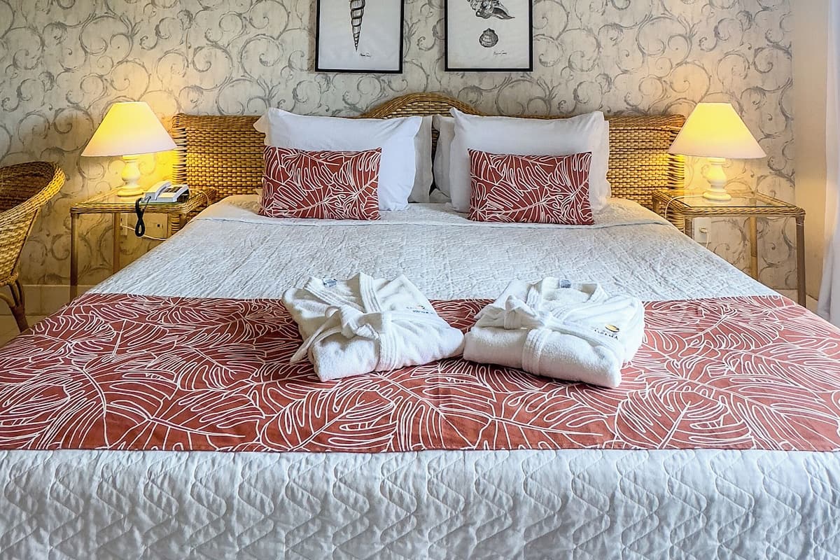 A neatly made bed with a patterned bedspread, two pillows, and two bedside lamps.