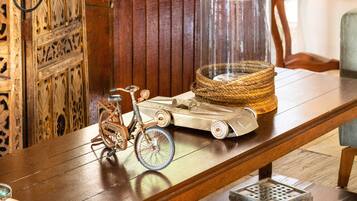Una mesa de madera con una bicicleta antigua, un coche modelo y un florero transparente con una cesta tejida.