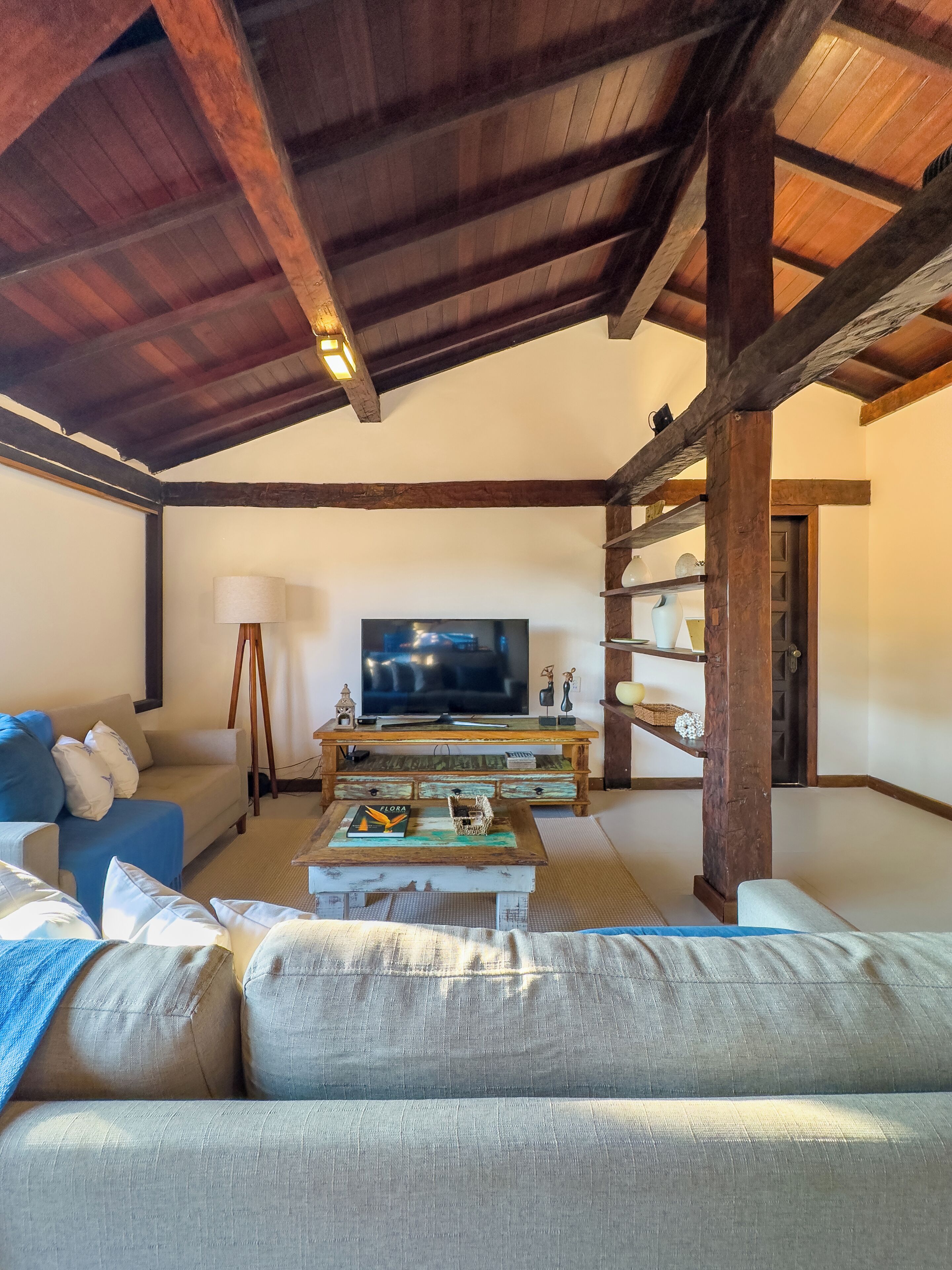 A cozy living room with a high ceiling, wooden beams, a television, a sofa, and a coffee table.