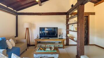 A cozy living room with a high ceiling, wooden beams, a television, a sofa, and a coffee table.