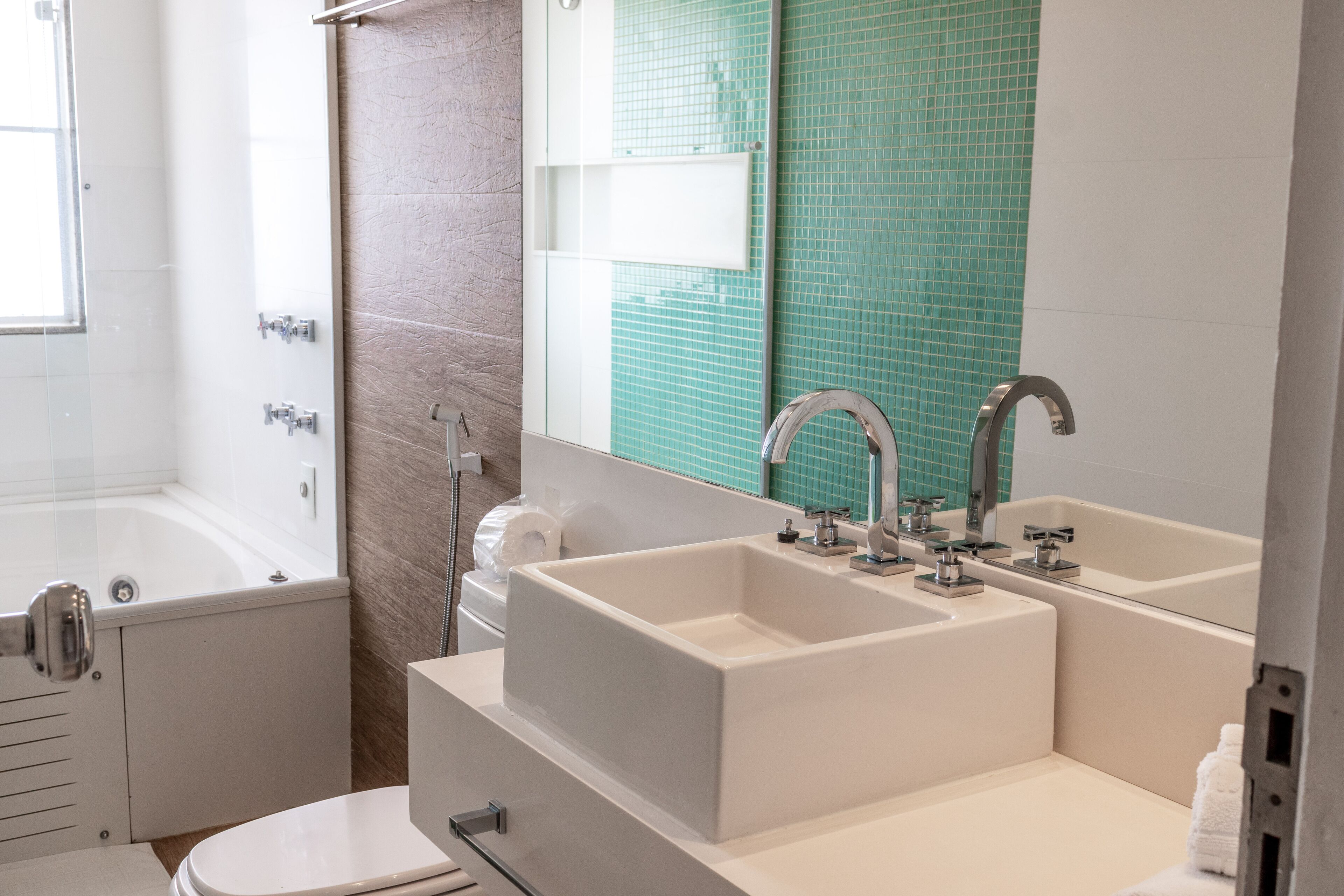 A bathroom with a bathtub, a double sink, and a toilet.