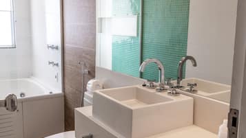 A bathroom with a bathtub, a double sink, and a toilet.