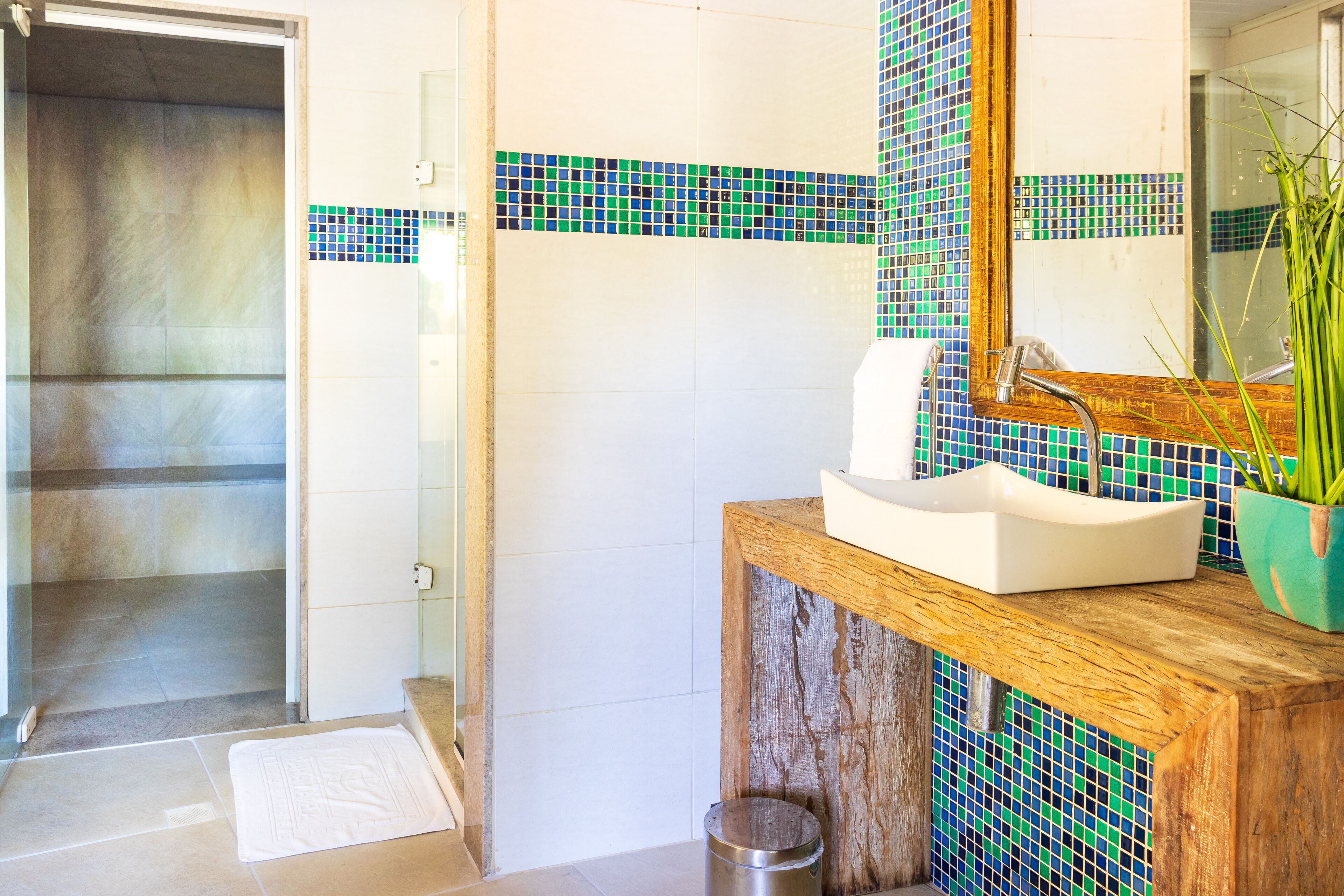 A bathroom with a shower, a sink with a wooden countertop, and a mirror.