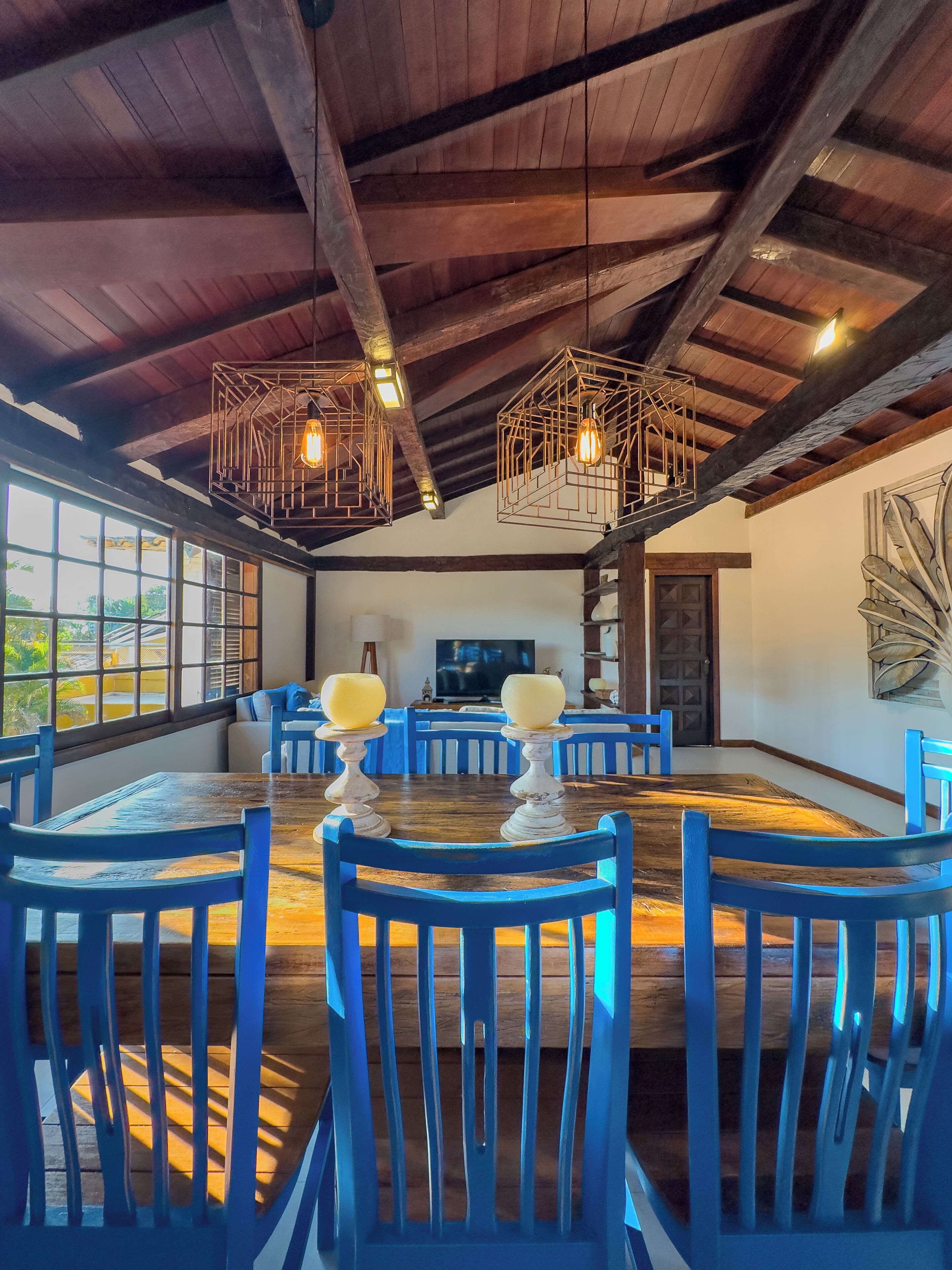 A dining area with a wooden table and blue chairs, a television, and a decorative wall piece.