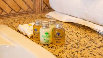 Una encimera de baño con artículos de tocador, incluyendo una botella de champú, acondicionador y gel de ducha de BAHIAMARELA Boutique Hotel.