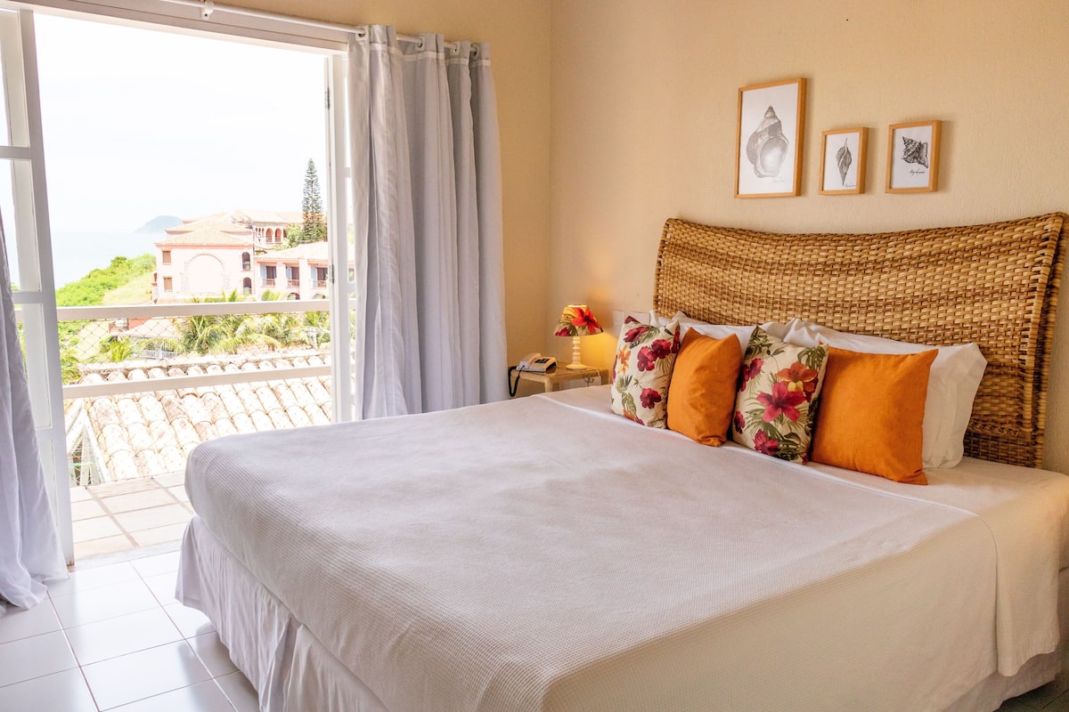 A bedroom with a large bed, a wicker headboard, and a view of a building through a window.