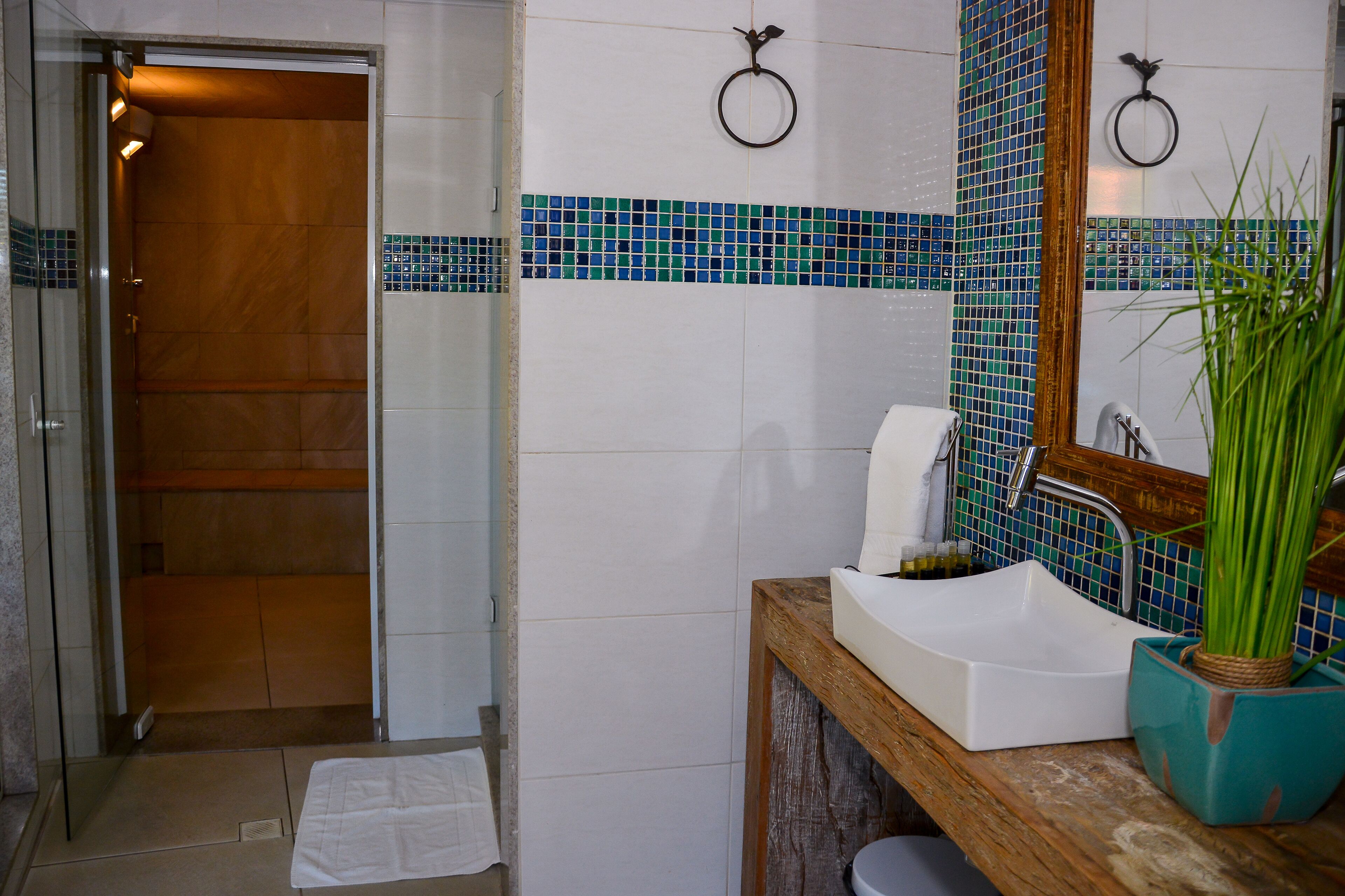 A bathroom with a wooden door, a white sink, a mirror, and a tiled backsplash.