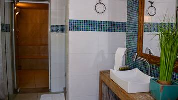 A bathroom with a wooden door, a white sink, a mirror, and a tiled backsplash.