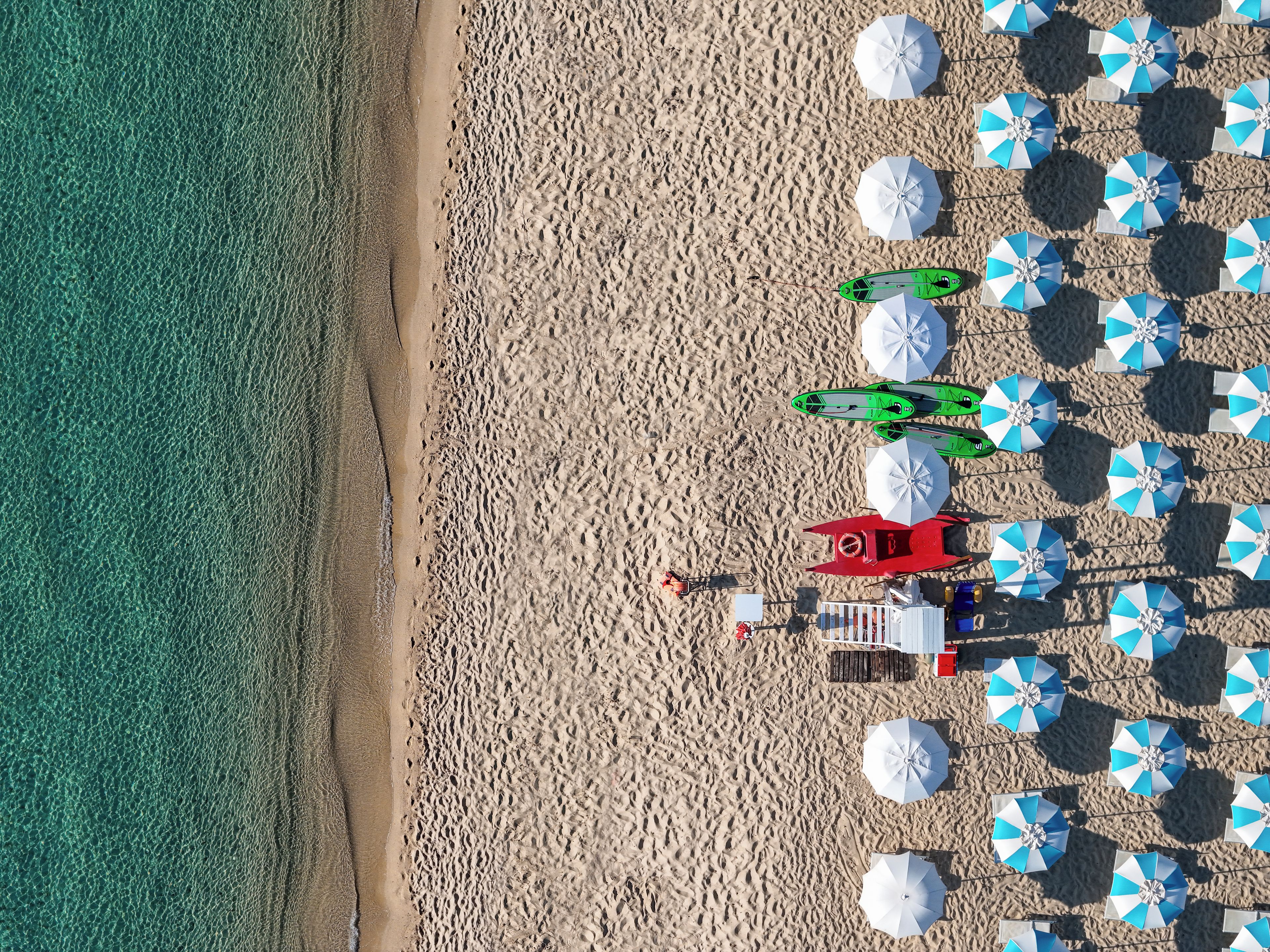 A beach with multiple umbrellas and a lifeguard tower.