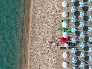 A beach with multiple umbrellas and a lifeguard tower.