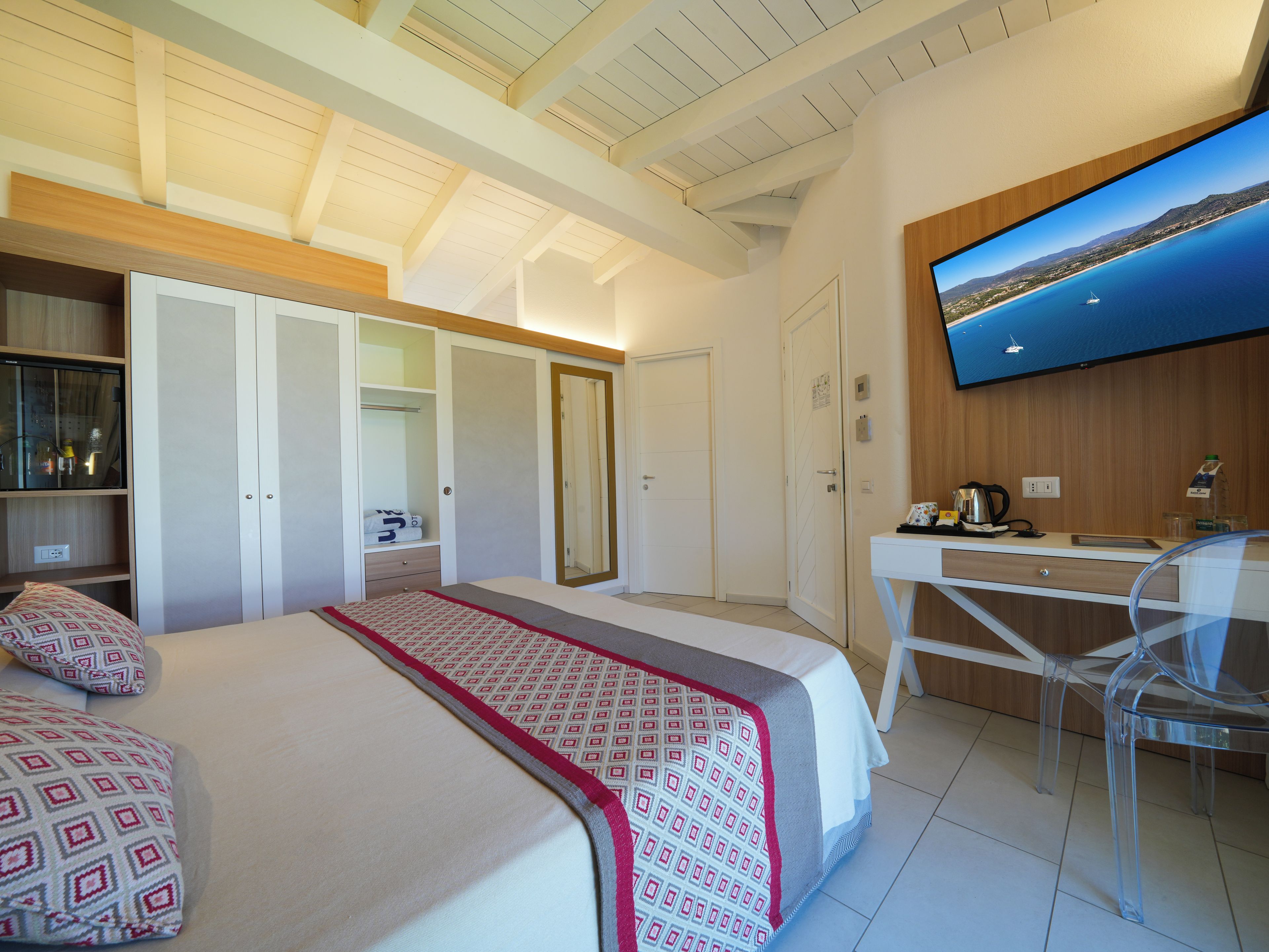 A hotel room with a bed, a desk, a TV, and a wardrobe.