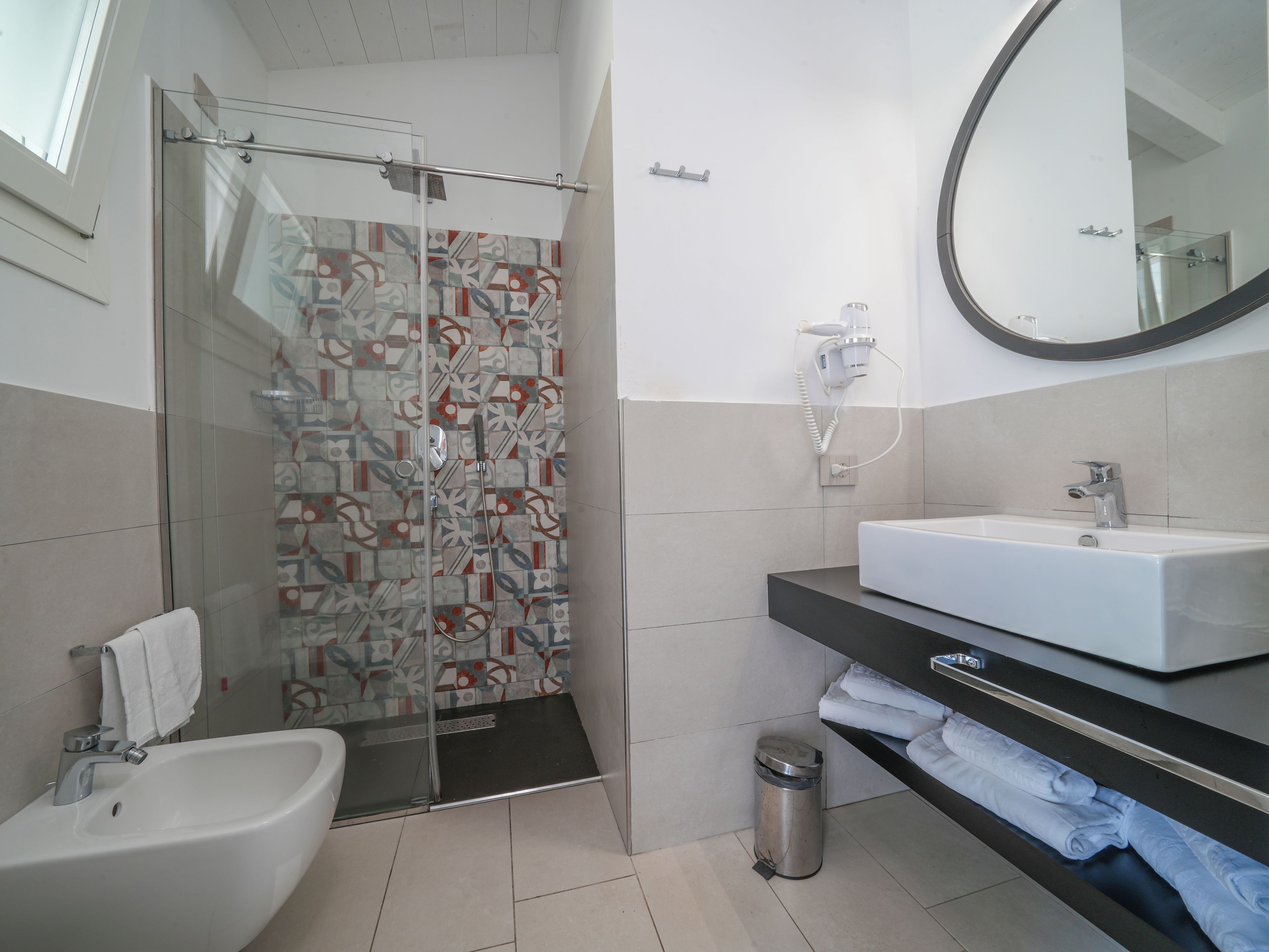 A modern bathroom with a glass-enclosed shower, a white sink, and a mirror.