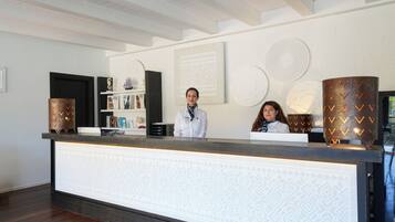 A reception desk with a patterned backdrop, a dark wooden floor, and a white ceiling with exposed beams.