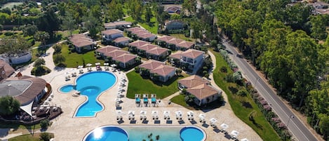 Un resort con varias piscinas, villas y vista al mar.