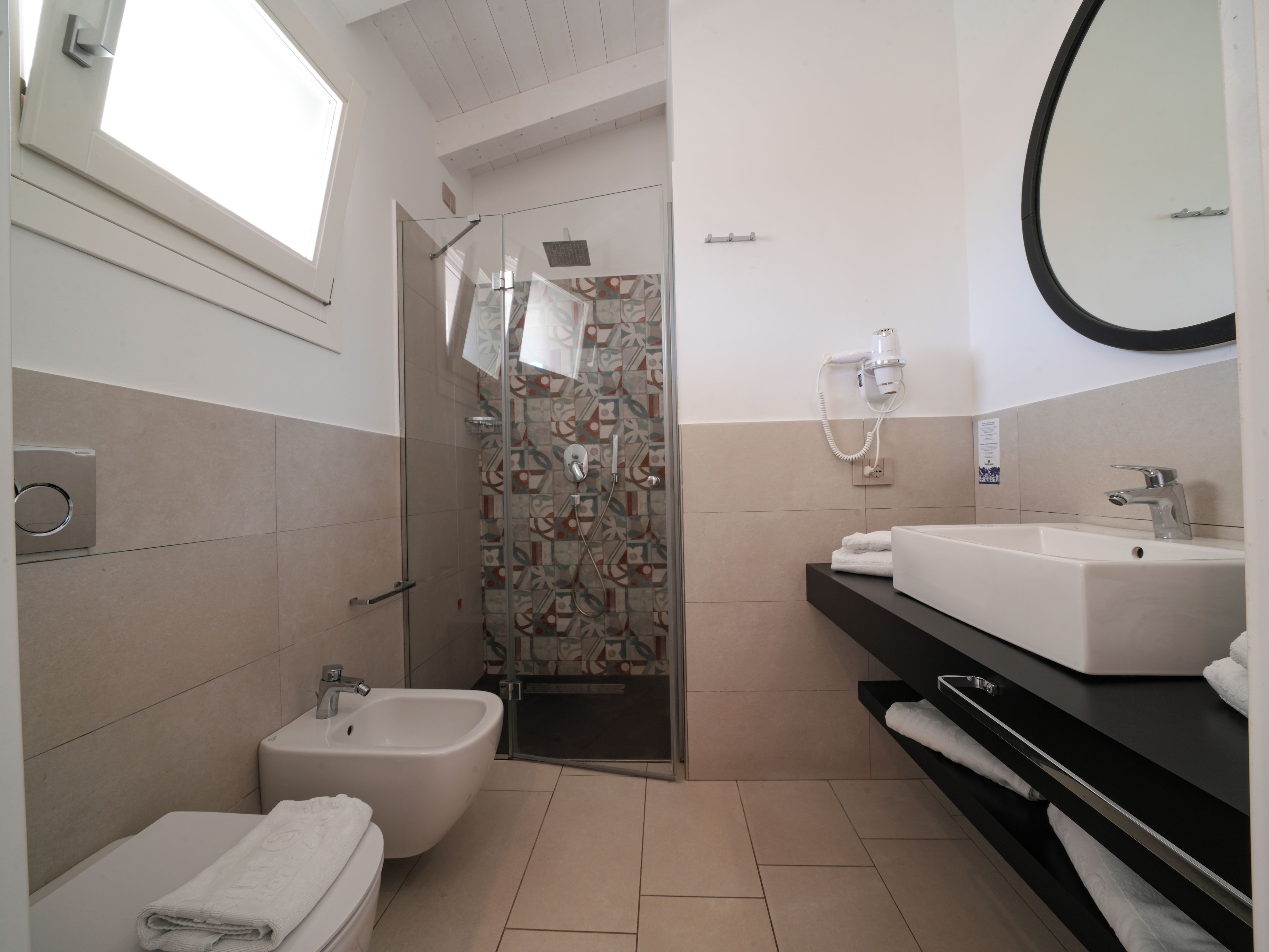 A modern bathroom with a bidet, a shower with a glass door, a sink with a mirror, and a towel rack.