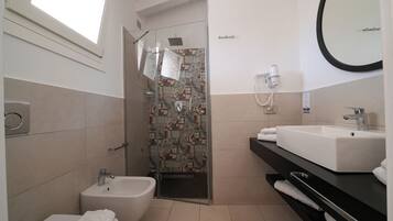 A modern bathroom with a bidet, a shower with a glass door, a sink with a mirror, and a towel rack.