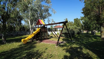 Un parque infantil con tobogán y columpios.