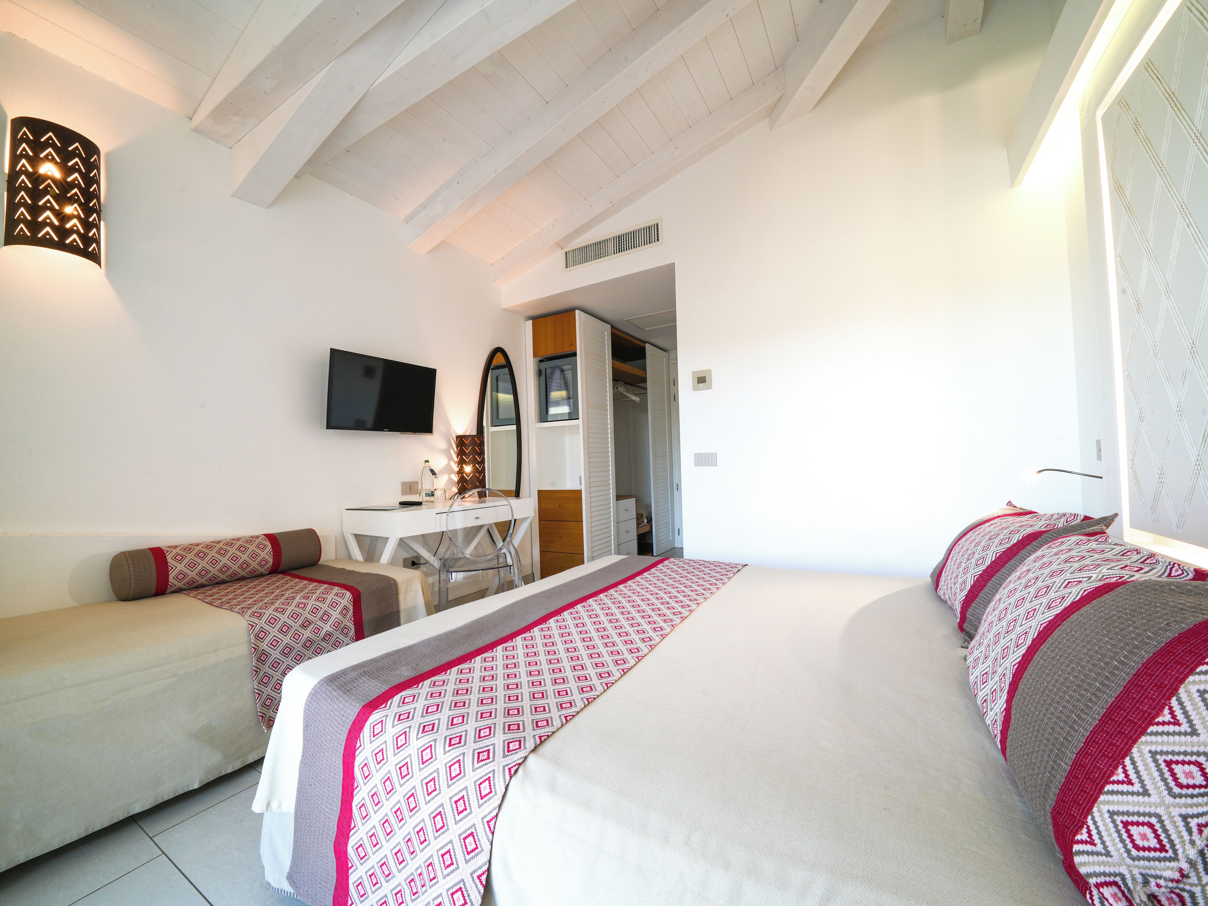 Un dormitorio con una cama, un escritorio, una silla y un televisor.