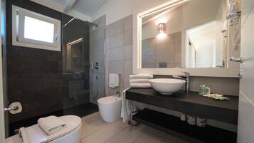 A modern bathroom with a toilet, bidet, sink, and shower.