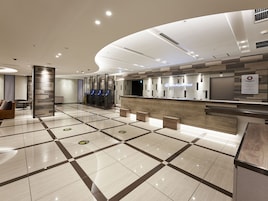 Uma área de recepção de hotel com design moderno, com balcão de atendimento, área de estar e balcão de check-in.