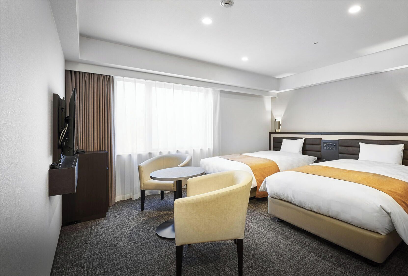 Une chambre d’hôtel avec deux lits, un bureau, une chaise et un téléviseur.