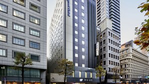 Ein modernes Hotelgebäude mit auffälliger Beschilderung, umgeben von anderen Hochhäusern.