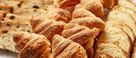 A variety of bread, including croissants and sliced bread, arranged on a tray.