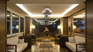 A modern lobby with a sofa, armchairs, a coffee table, and a chandelier. - Nidya Hotel Galataport (Istanbul)