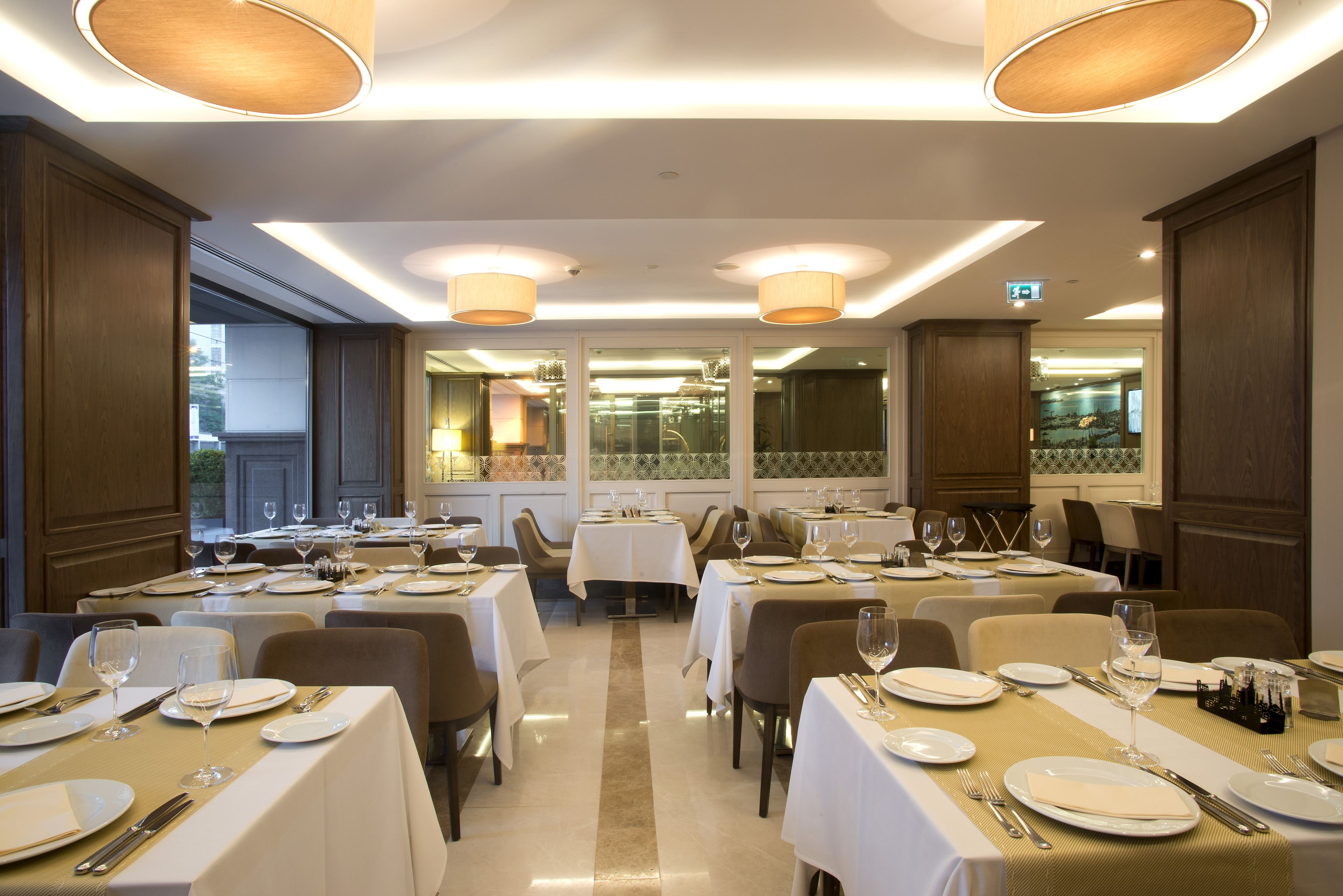 A restaurant with multiple tables set for dining, featuring white tablecloths and a clean, modern interior.