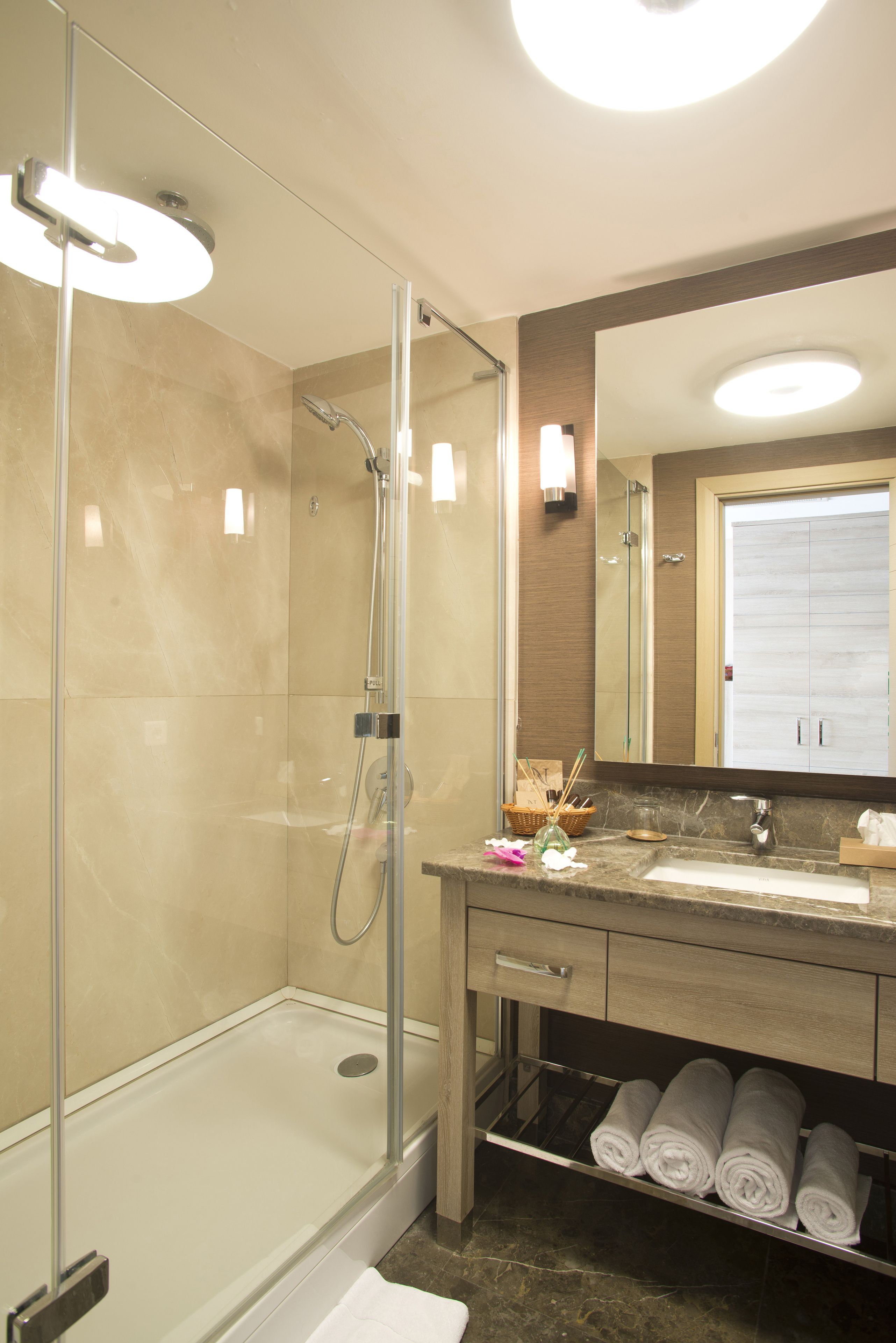Un baño moderno con ducha de vidrio, tocador con lavamanos y espejo.