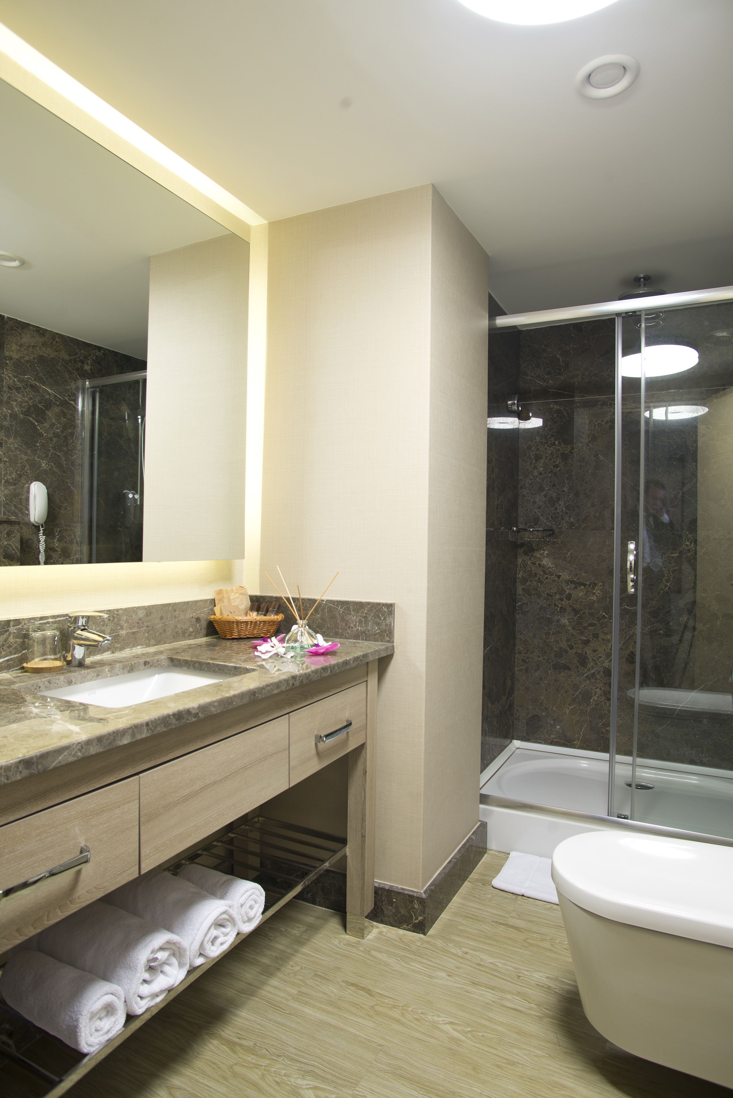 A modern bathroom with a marble sink, a glass-enclosed shower, and a white toilet.