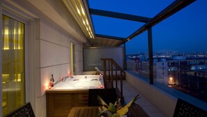 A rooftop terrace with a hot tub, wooden furniture, and a city view at dusk. - Nidya Hotel Galataport (Istanbul)