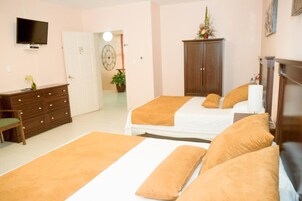 Un dormitorio con dos camas, un aparador, un televisor y una puerta que da a otra habitación.