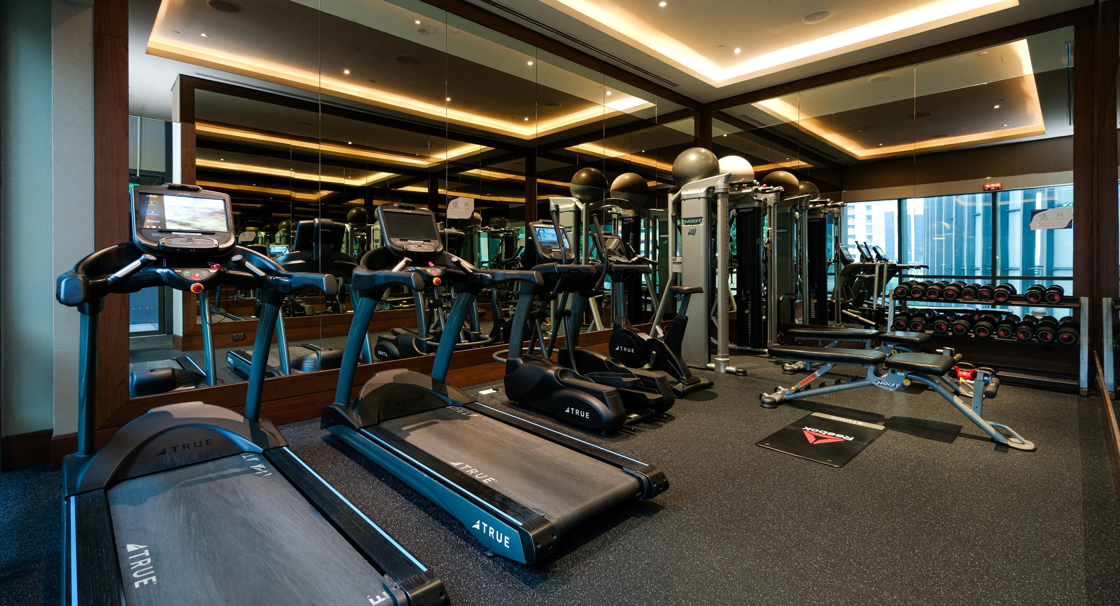 Una palestra attrezzata con tapis roulant, ellittiche e macchinari per sollevamento pesi.