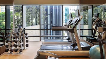 A gym with exercise equipment, large windows, and a view of buildings.