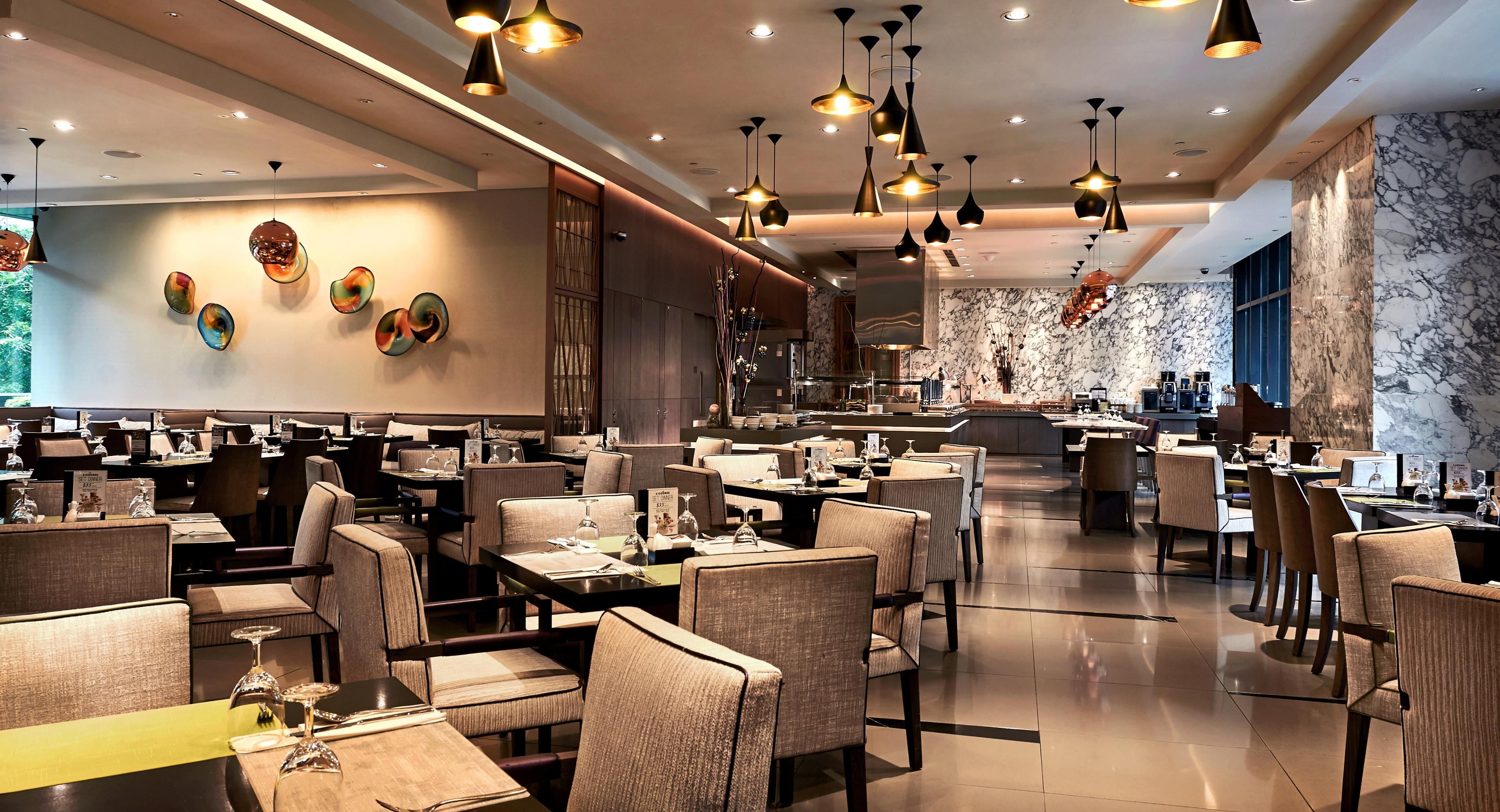 Un restaurant doté de nombreuses tables et chaises, d’un éclairage au plafond et d’un mur en marbre.