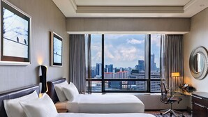 A hotel room with two beds, a desk, a chair, and a large window offering a city view. - Carlton City Hotel Singapore (Singapore)