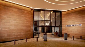 A modern hotel lobby with wooden paneling, large glass doors, and a central light fixture. - Carlton City Hotel Singapore (Singapore)