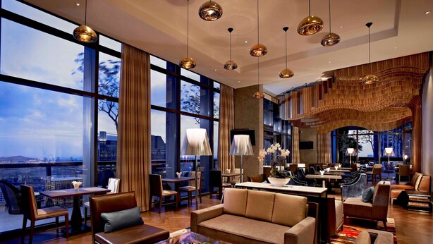 A spacious lounge area with large windows, modern furniture, and a view of the cityscape. - Carlton City Hotel Singapore (Singapore)