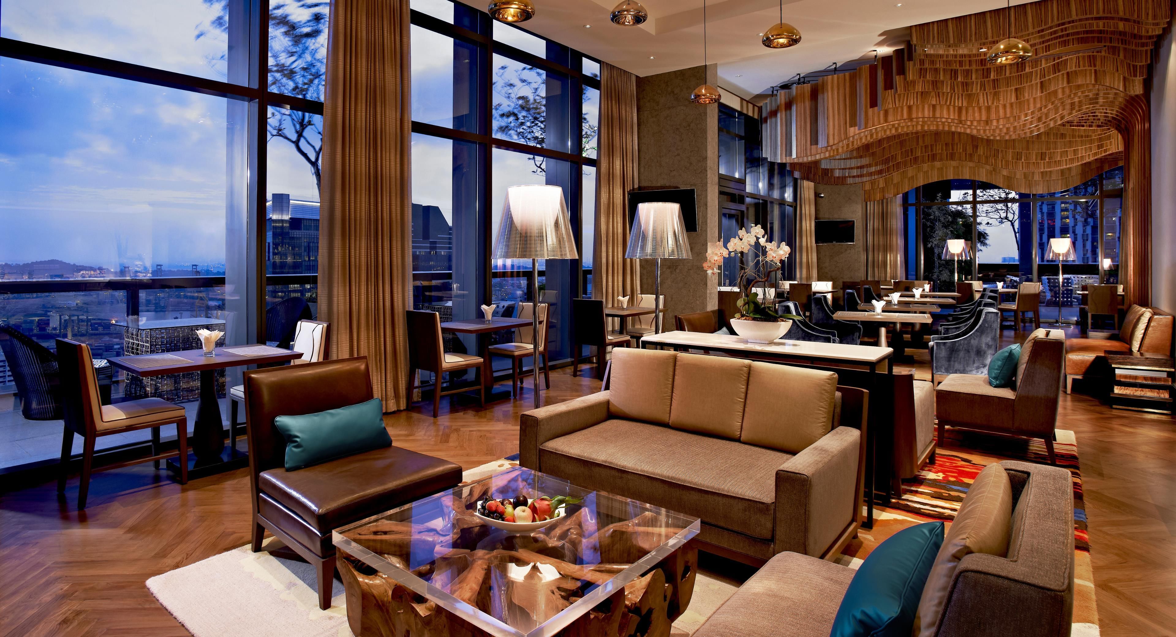 Un moderno vestíbulo de hotel con un amplio espacio de estar, un bar y vistas a la ciudad.