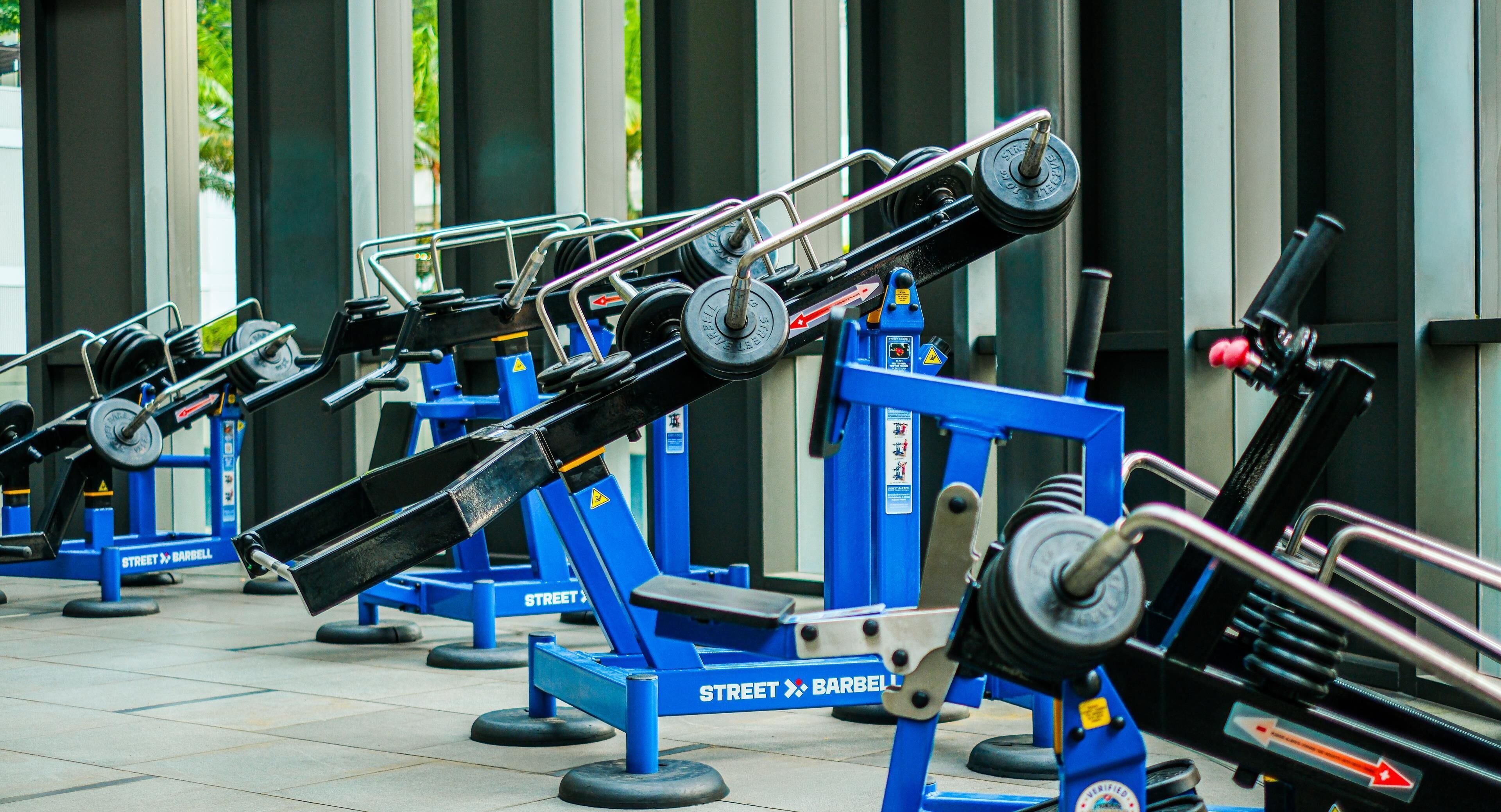A row of outdoor exercise equipment with weights and bars.