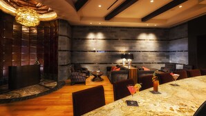 Un área de estar moderna con barra de mármol, asientos y una lámpara decorativa.