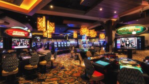 Un salón de casino con máquinas tragamonedas, mesas de juego y zonas de estar cómodas.