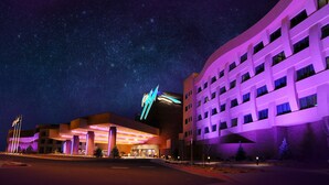 Un hotel de diseño moderno, con un llamativo letrero de neón y una amplia zona de estacionamiento.
